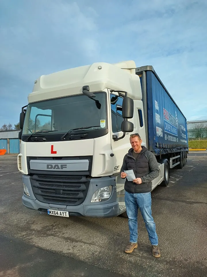 Driver celebrating a test pass beside a DAF lorry Pole Position Driver Training